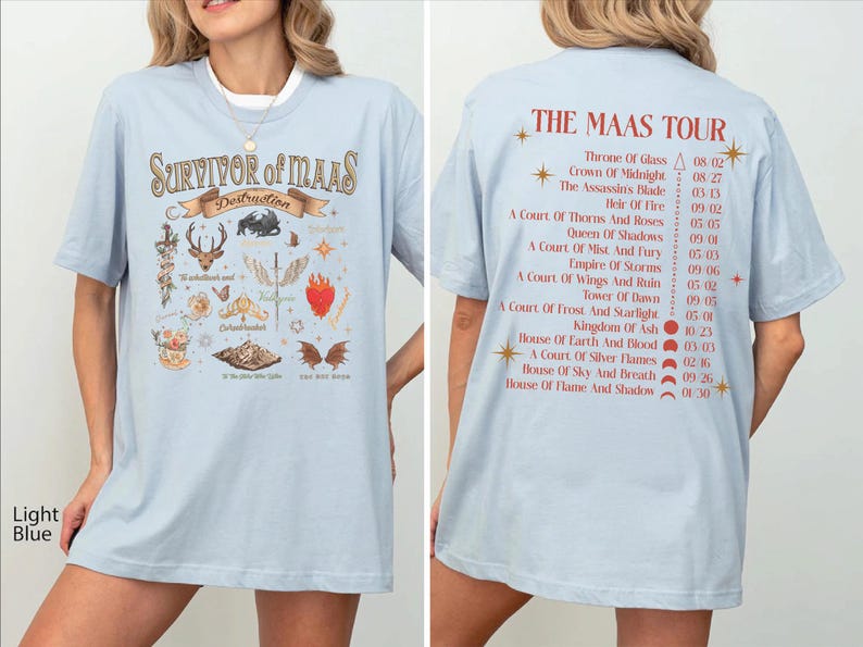 a woman wearing a light blue t-shirt with a graphic design featuring various symbols and text related to the Maas Tour.