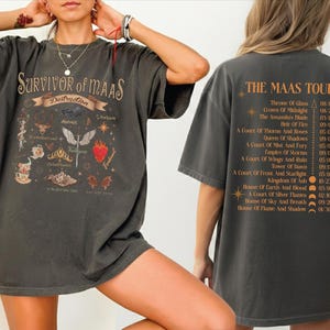 A person wearing a black t-shirt with a graphic design and text, posing with their hands on their head.