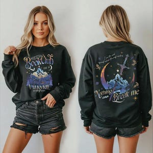 A woman wearing a black sweatshirt with a graphic design on the front and back.