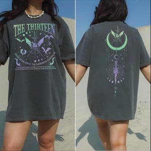The image is a collage of two photos of a person wearing a grey t-shirt with a design featuring bats, a crescent moon, and a dragon. The person is standing in front of a sandy background.