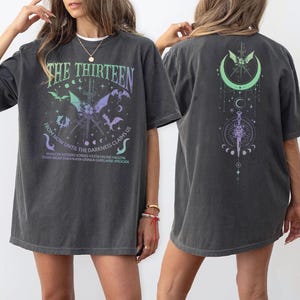 a woman wearing a gray t-shirt with a graphic design on the front and back.