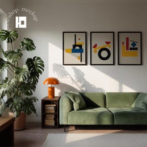May include: A modern living room featuring a green velvet sofa, three framed abstract art prints, and an orange table lamp. A large potted plant sits to the left, with a wooden side table holding books. The room has a minimalist design.