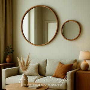 Two round wooden mirrors in different sizes hanging on a modern living room wall, creating a balanced composition with natural oak tones and neutral decor.
