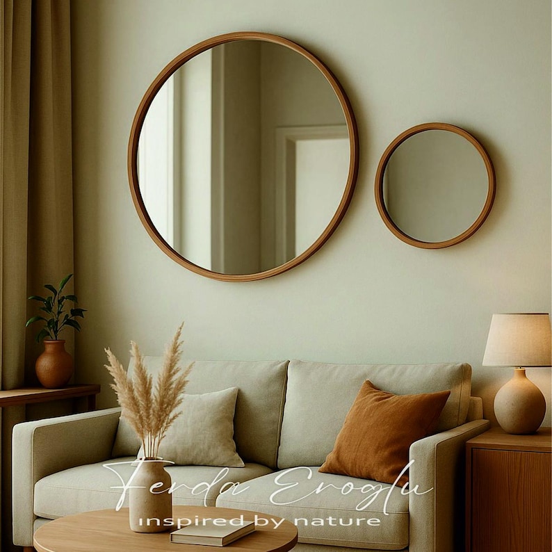 Two round wooden mirrors in different sizes hanging on a modern living room wall, creating a balanced composition with natural oak tones and neutral decor.
