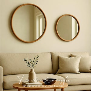 Two round wooden framed mirrors hanging on a beige living room wall, reflecting natural light and adding warmth and depth to the space.