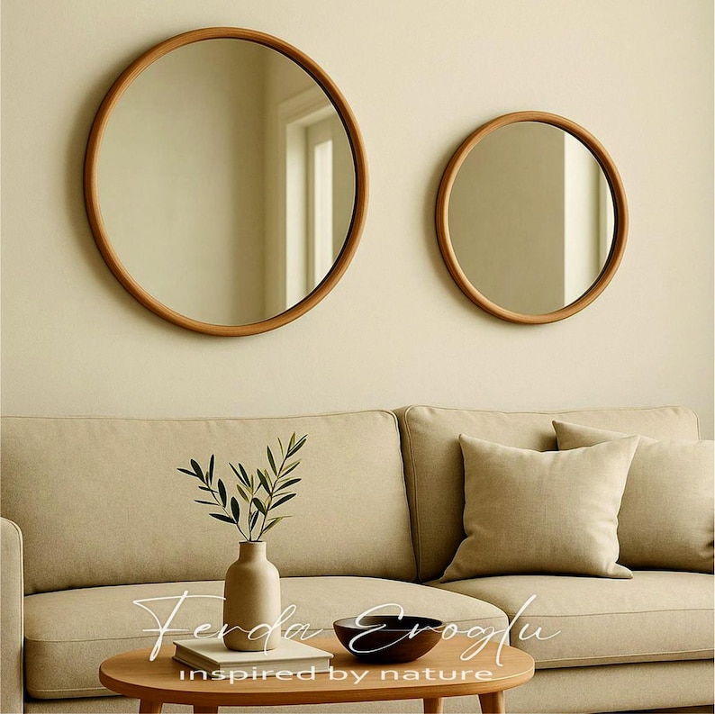 Two round wooden framed mirrors hanging on a beige living room wall, reflecting natural light and adding warmth and depth to the space.