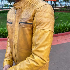 K&ouml;nnte beinhalten: Senfgelbe Lederjacke mit einem gesteppten Schulterdesign und zwei Brusttaschen mit Rei&szlig;verschluss. Die Jacke hat einen Stehkragen und einen Frontrei&szlig;verschluss. Die &Auml;rmel sind lang und tailliert, und das Leder hat ein leichtes Used-Look-Aussehen.