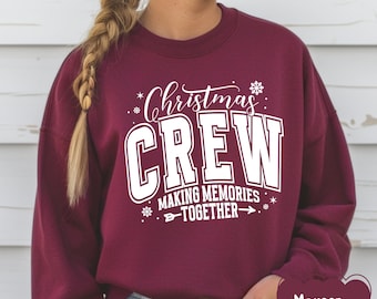 May include: Maroon sweatshirt with the text "Christmas CREW MAKING MEMORIES TOGETHER" in white. The sweatshirt has a crew neck and long sleeves. The text includes snowflake and star graphics.