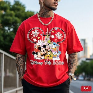 May include: Red t-shirt featuring a Mickey Mouse-shaped design with Disney characters, a castle, and the text "Disney Trip 2020". The design includes Mickey, Minnie, Goofy, Donald Duck, and other characters.
