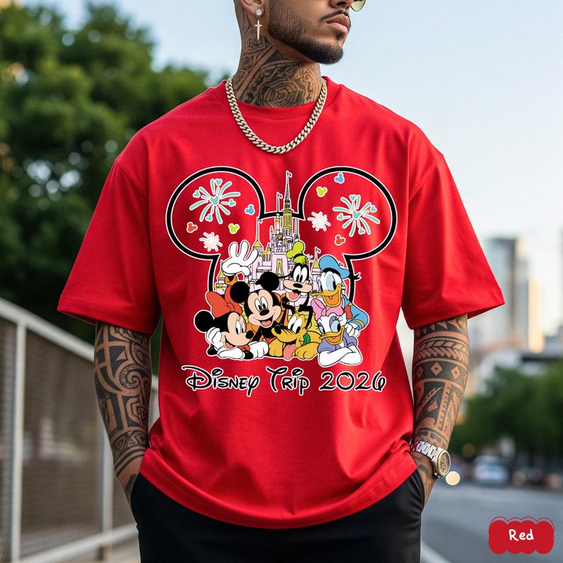 May include: Red t-shirt featuring a Mickey Mouse-shaped design with Disney characters, a castle, and the text "Disney Trip 2020". The design includes Mickey, Minnie, Goofy, Donald Duck, and other characters.