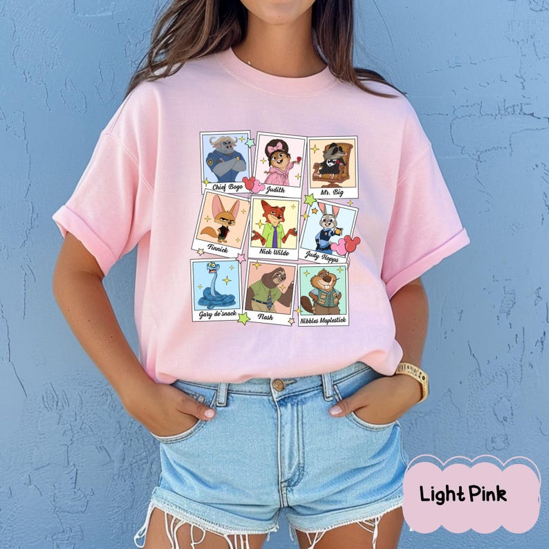 Peut inclure: T-shirt rose clair avec une grille de portraits de personnages de dessins anim&eacute;s. Chaque portrait est encadr&eacute; d'un bord blanc et comprend les noms des personnages. Le texte "Light Pink" est en bas &agrave; droite.