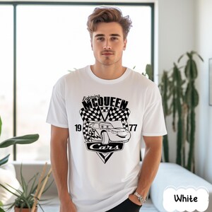 May include: White t-shirt with a black graphic of Lightning McQueen from the film Cars. The design includes a chequered flag, the number 95, and the text "Lightning McQueen" and "Cars". The shirt has a crew neck.