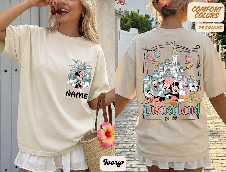 Puede incluir: Camiseta de color marfil con un gr&aacute;fico de Minnie Mouse y la palabra "NAME" en la parte delantera. La parte trasera muestra un gr&aacute;fico de Disneyland con personajes de dibujos animados y el texto "Disneyland Est. 1955".