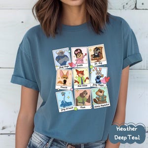 Peut inclure: T-shirt bleu sarcelle avec une grille de portraits de personnages de dessins anim&eacute;s. Chaque portrait est dans un cadre de style polaroid avec les noms des personnages en dessous. Le t-shirt porte &eacute;galement le texte "Heather Deep Teal".