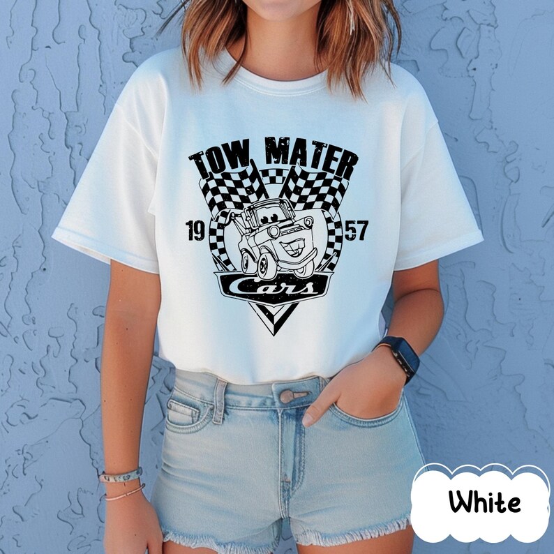 May include: White t-shirt with a black and white graphic of Tow Mater from the Cars film. The design includes the text "TOW MATER", "CARS", and the numbers "19" and "57". The shirt has short sleeves and a crew neck.