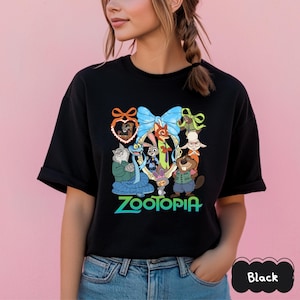 Może przedstawiać: Czarny t-shirt z kolorową grafiką postaci z filmu animowanego Zwierzogr&oacute;d. Projekt zawiera niebieską kokardę i napis "Zootopia" w kolorze zielonym i niebieskim. Koszulka ma okrągły dekolt.