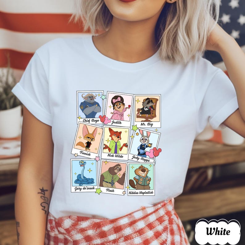 Peut inclure: T-shirt blanc avec des portraits de personnages de dessins anim&eacute;s d'un film. Les personnages incluent Chief Bogo, Judith, Mr. Big, Finnick, Nick Wilde, Judy Hopps, Gary de'snack, Flash et Nibbles Maplestick. Le mot "White" est imprim&eacute; en bas &agrave; droite.
