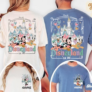 Puede incluir: Camisetas marfil y azul vaquero con un dise&ntilde;o de Disneyland que muestra a Mickey, Minnie, Donald, Daisy y Goofy frente a un castillo. Las camisetas tienen el texto "Disneyland Est. 1955". Disponibles en 19 colores.