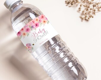 Pode incluir: Uma garrafa de água de plástico transparente com tampa branca. A garrafa tem um rótulo com as palavras "Baby Shower" em rosa, rodeado por flores em aquarela em rosa, pêssego e roxo. Uma pequena abelha é visível.