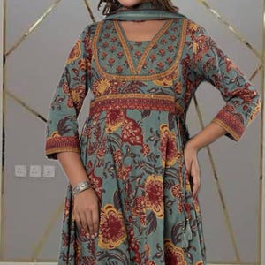 May include: A teal-colored dress with a floral pattern in red and yellow. The dress has long sleeves and a V-neckline with a matching scarf. The waist is cinched with a red and gold band. The dress is a flowing, feminine style.