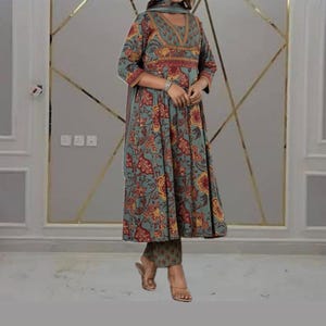 May include: A teal, floral-print ensemble featuring a long-sleeved tunic with a flared skirt, matching pants, and a scarf. The tunic has a V-neckline and is adorned with red and yellow floral patterns. The outfit is suitable for various occasions.