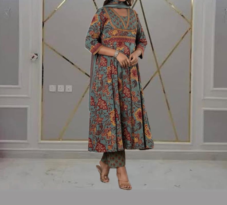 May include: A teal, floral-print ensemble featuring a long-sleeved tunic with a flared skirt, matching pants, and a scarf. The tunic has a V-neckline and is adorned with red and yellow floral patterns. The outfit is suitable for various occasions.