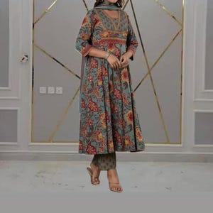 May include: A teal, floral-print ensemble featuring a long-sleeved tunic, matching pants, and a scarf. The tunic has a V-neckline and a flared silhouette. The floral pattern includes red and yellow accents. The outfit is suitable for casual or semi-formal occasions.