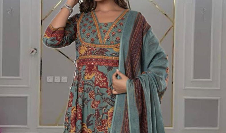 May include: A teal-colored, long-sleeved dress with a floral pattern in red and yellow. The dress features a V-neckline with intricate gold and red embroidery. A matching teal shawl with a patterned border drapes over the shoulders.