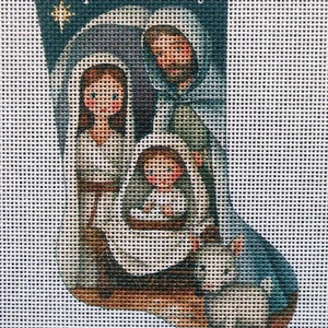 May include: A Christmas stocking with a blue background and a depiction of the nativity scene. Mary, Joseph, and baby Jesus are shown in the center of the stocking, with a white lamb at the bottom.