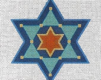 May include: A needlepoint design of a Star of David. The star features a blue outline, with turquoise and orange inner stars. The design is on a white, dotted background. The star has yellow accents.
