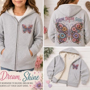 May include: A heather gray zip-up hoodie with a white fleece lining, featuring a small butterfly graphic on the front left chest and a large, colorful floral butterfly design on the back with the text Grow, Dream, Shine printed above it.