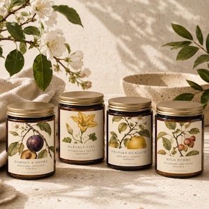 Puede incluir: Cuatro velas en frasco de vidrio ámbar con tapas doradas, cada una con una etiqueta de ilustración botánica. Las etiquetas se titulan Damson & Smoke, Harvest Vine, Orchard Heirloom y Wild Pomme, con 227g impresos en cada etiqueta.