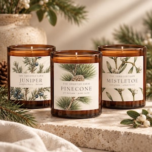 Puede incluir: Tres velas de vidrio ámbar con etiquetas blancas. La etiqueta izquierda dice THE THRIFTED FARM JUNIPER juniper berry balsam. La etiqueta central dice THE THRIFTED FARM PINECONE fir balsam pine resin. La etiqueta derecha dice THE THRIFTED FARM MISTLETOE evergreen white berry.