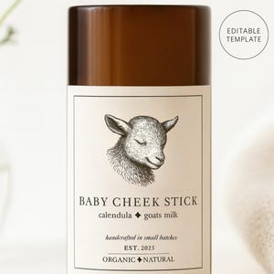 May include: A brown cylindrical container with a label featuring a detailed illustration of a lamb's head. The label reads "BABY CHEEK STICK" with "calendula goats milk" and "handcrafted in small batches". The text "EST. 2025" and "ORGANIC NATURAL" are also visible.