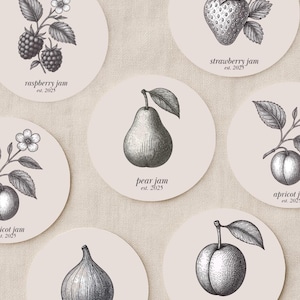 Op de afbeelding: Een verzameling ronde onderzetters met gedetailleerde zwart-wit illustraties van diverse vruchten, waaronder frambozen, aardbeien, peren, abrikozen, vijgen en pruimen. Elke onderzetter is gelabeld met de fruitnaam en "est. 2025".