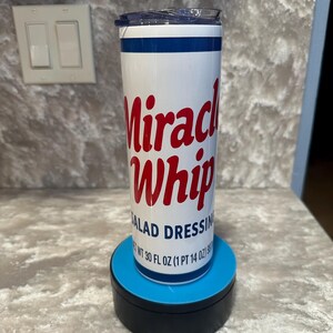 May include: A white tumbler with a blue and red design. The tumbler features the words "Miracle Whip" in red script, with "SALAD DRESSING" below. The tumbler is 887 ml and has a blue lid.