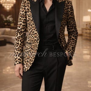 Könnte beinhalten: Ein Blazer mit Leopardenmuster mit schwarzen Revers und einem schwarzen Button-Down-Hemd. Der Blazer hat ein braunes und beigefarbenes Fleckenmuster. Die Person trägt eine schwarze Hose und einen schwarzen Gürtel. Der Text "march BESPOKE" ist auf dem Blazer zu sehen.