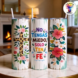 May include: Three white insulated tumblers with lids and straws. One features a cross with a leopard print design, surrounded by flowers. Another has the text "NO TENGAS MIEDO, SOLO TEN FE." The third has floral designs.