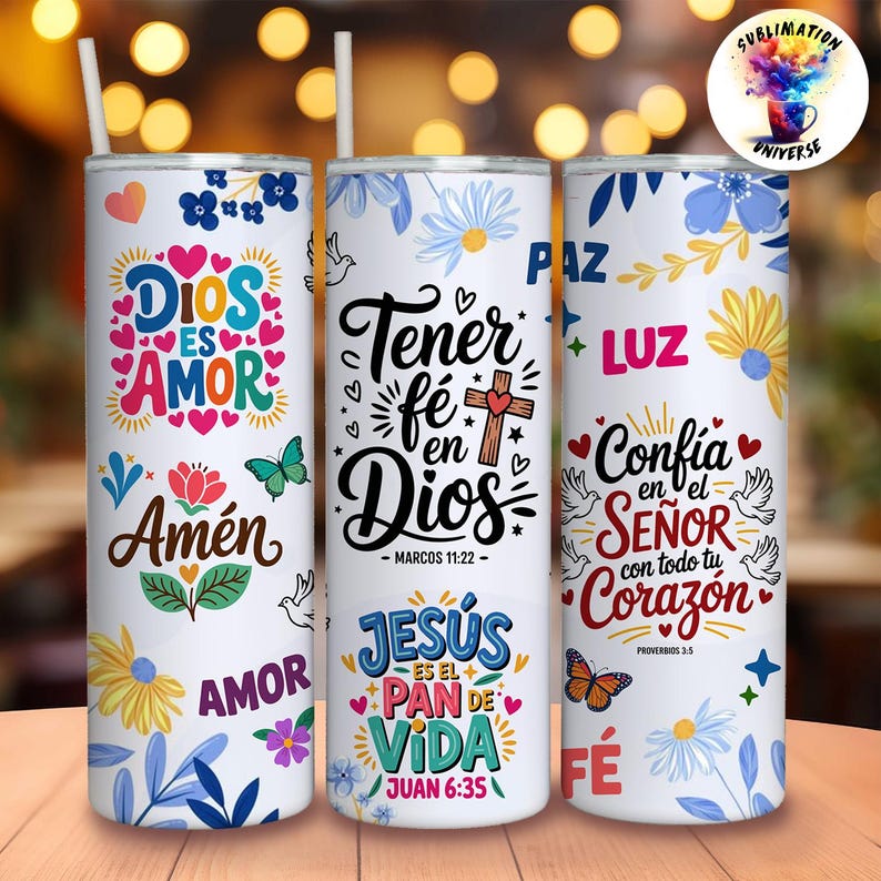 May include: Three white insulated tumblers with floral and religious designs. Each tumbler features text in Spanish, including "Dios es Amor" and "Tener fe en Dios." The tumblers have a straw and are decorated with butterflies and flowers.