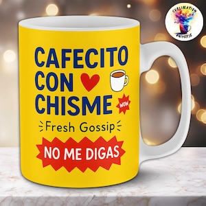 May include: A yellow ceramic mug with the words "CAFECITO CON CHISME" in blue, a red heart, and a coffee cup illustration. Below, it says "Fresh Gossip" and "NO ME DIGAS" in a red starburst. The mug has a white handle.