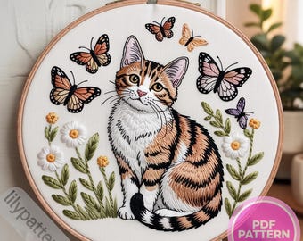 May include: Embroidered artwork featuring a tabby cat surrounded by butterflies and flowers. The cat has brown and orange stripes, with white accents. Butterflies in shades of orange, black, and purple are scattered around the cat. The embroidery is set in a wooden hoop.