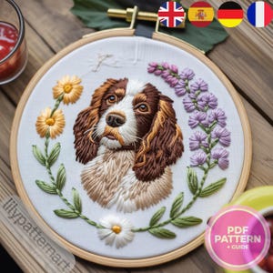 May include: Embroidery hoop art featuring a detailed, hand-stitched portrait of a dog with brown and white fur. The design includes yellow and white flowers, green leaves, and purple floral accents. The text "PDF PATTERN + GUIDE" is visible.