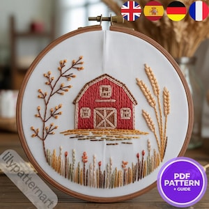 Peut inclure: Broderie sur tissu blanc dans un cercle en bois. La scène représente une grange rouge avec des détails de blé et de feuillage. Le texte "lilypatternart" est visible. Un motif PDF est également inclus.