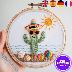 Peut inclure: Broderie sur cercle représentant un cactus souriant portant des lunettes de soleil et un sombrero avec le mot "HOLA!". Le motif comprend un soleil, des ballons de plage, des coquillages et des vagues, le tout dans des couleurs vives. L'œuvre est sur fond blanc.