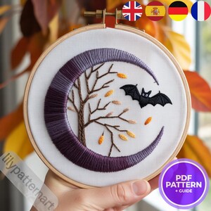 Peut inclure: Un cercle de broderie avec un motif de croissant de lune violet, un arbre et des feuilles tombantes marron et orange. Une chauve-souris noire vole près de la lune. Le texte "PDF PATTERN + GUIDE" est visible.