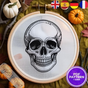 Peut inclure: Broderie d'un crâne noir et blanc sur tissu blanc, dans un cercle de bois. Le crâne est détaillé. L'image comprend des citrouilles miniatures et des feuilles d'automne.