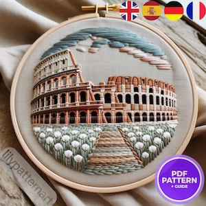 Peut inclure: Broderie sur tambour représentant le Colisée de Rome. L'œuvre utilise des nuances de marron, beige et vert pour représenter l'amphithéâtre antique, avec un ciel bleu et des fleurs blanches. Le texte "lilypatternart" est visible.