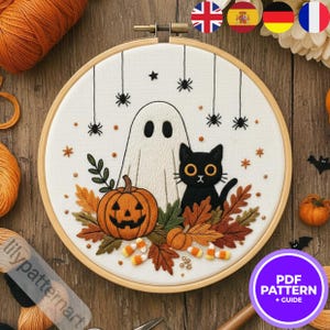 Peut inclure: Broderie sur le thème d'Halloween dans un cercle en bois. L'image présente un fantôme blanc, un chat noir et une citrouille sculptée. Araignées, étoiles et feuilles d'automne complètent le motif. Du fil orange et marron est visible.