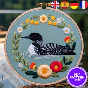 Peut inclure: Broderie d'un huard dans un cercle en bois. Le huard est noir et blanc avec un œil rouge, entouré d'une couronne florale de fleurs jaunes, blanches et rouges et de feuilles vertes. Le texte "PDF PATTERN + GUIDE" est dans un cercle violet.