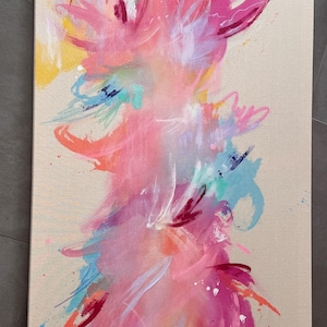 May include: A rectangular canvas painting featuring an abstract composition with vibrant splashes and brushstrokes of hot pink, magenta, orange, yellow, and light blue against a neutral beige background, creating a dynamic and layered visual effect.